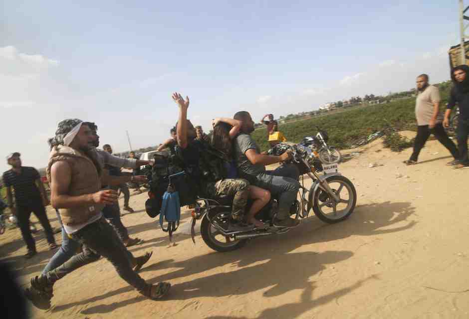 Alcuni militanti di Hamas trasportano un civile israeliano catturato nel kibbutz di Kfar Azza/ Ansa