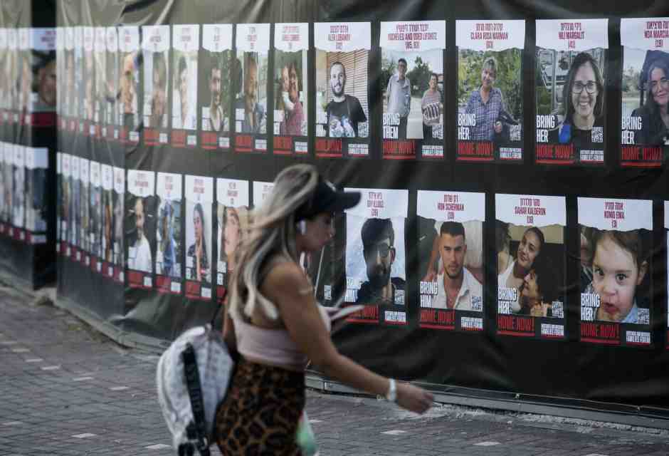 Una donna cammina accanto a manifesti con foto degli ostaggi israeliani nelle mani di Hamas. Hadera, Israele (Amir Levy/Getty Images) 