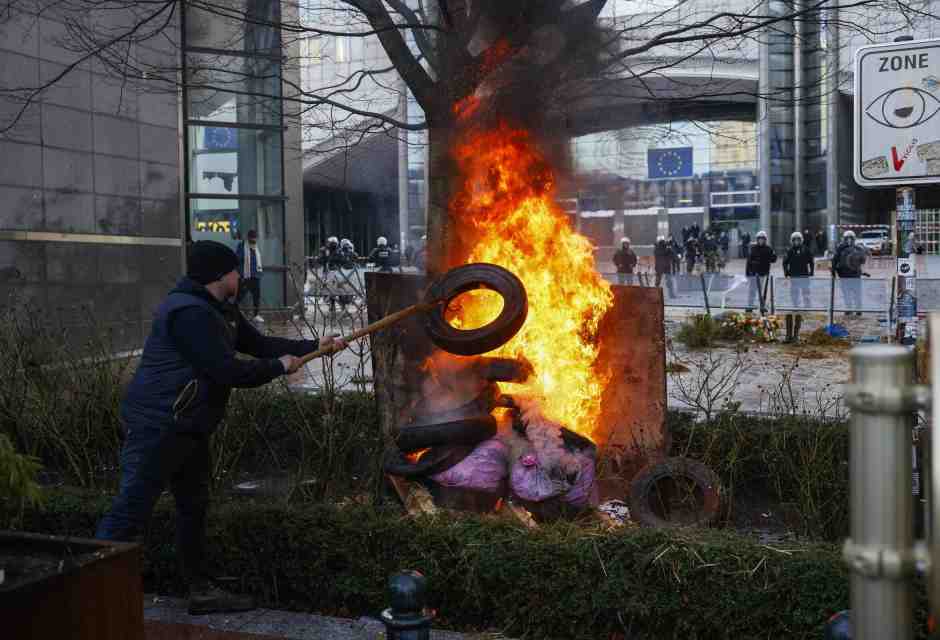&nbsp;Un manifestante brucia dei rifiuti davanti alle istituzioni europee a Bruxelles - foto Ansa
