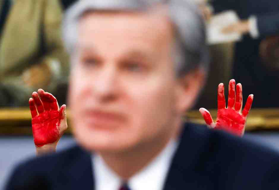 &nbsp;I palmi macchiati di rosso di un manifestante per le vittime di Gaza dietro a Christopher Wray, capo del Federal Bourau of Investigation