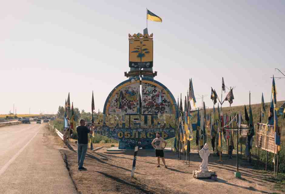 Uomini si fermano davanti a un cartello che segnala l'ingresso all'area di Donetsk, parte della regione ucraina del Donbas. <br /><br />Credits: Alice Martins per il Washington Post