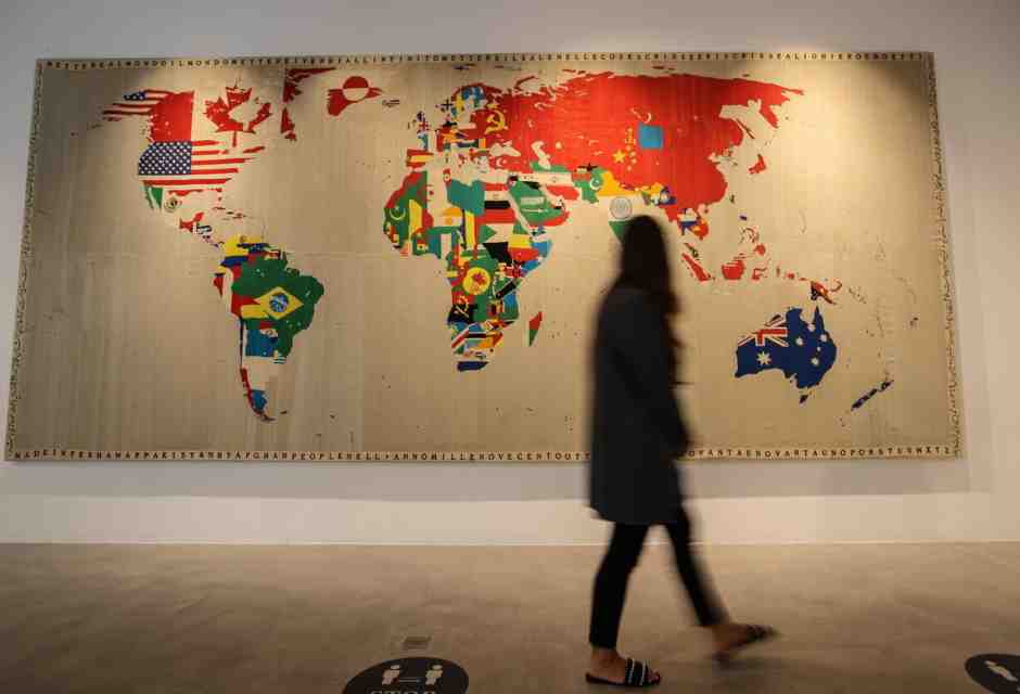 Una donna cammina davanti a un'opera della famosa serie di mappe ricamate di Boetti, nella galleria Sotheby's Dubai nel 2022 (Ansa)&nbsp;<br />