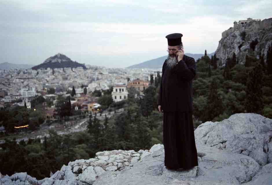 Un sacerdote parla al cellulare in cima alla collina dell'Areòpago ad Atene (Foto di Jean-Noel DE SOYE/via Getty Images) <br />