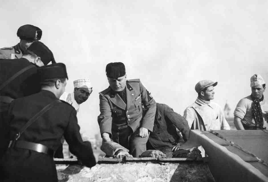 Benito Mussolini posa una piastrella all'inizio della costruzione di un nuovo edificio a Roma, il 19 febbraio 1935 (Gamma-Rapho via Getty Images)&nbsp;<br />