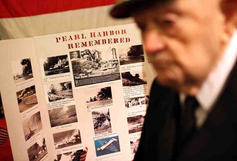 Il cappellano della USS Hornet, John Berger, accanto a un manifesto commemorativo di Pearl Harbor (Justin Sullivan/Getty Images)&nbsp;<br />