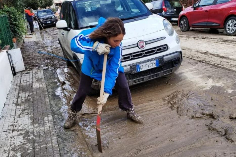 Una ragazza mentre spala il fango in una via di Prato - G. Cocchi