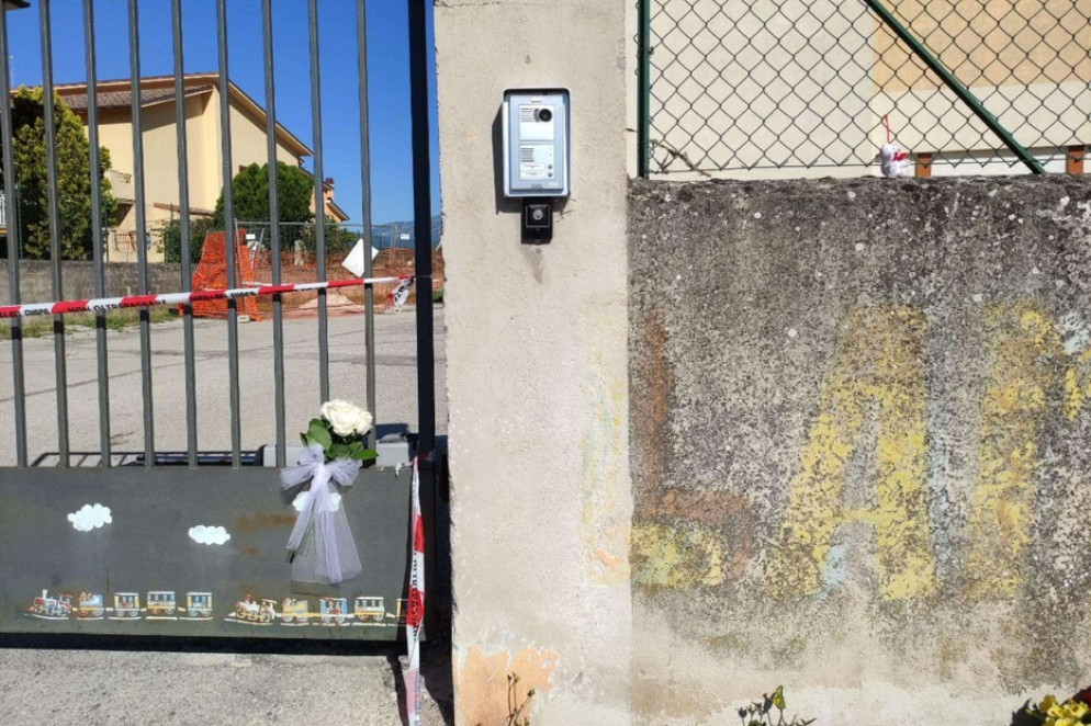 Una rosa bianca di fiori sul cancello chiuso della scuola d'infanzia dove è avvenuta la tragedia - Ansa