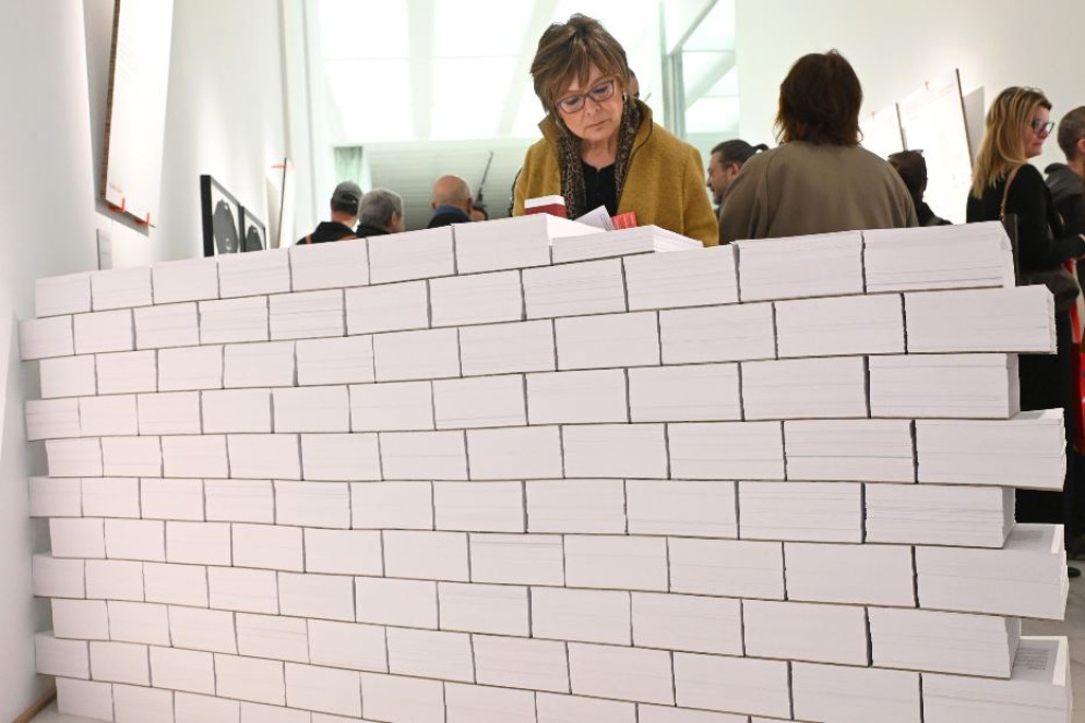 Una visitatrice osserva uno dei fogli che compongono l'opera "No more walls" alla mostra Contro la guerra alla Triennale di Milano - ANSA