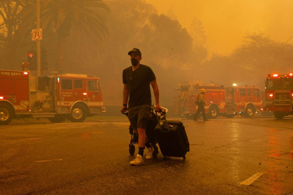 Un residente di Pacific Palisades lascia il quartiere, avvolto dai fumi dell'incendio - Fotogramma