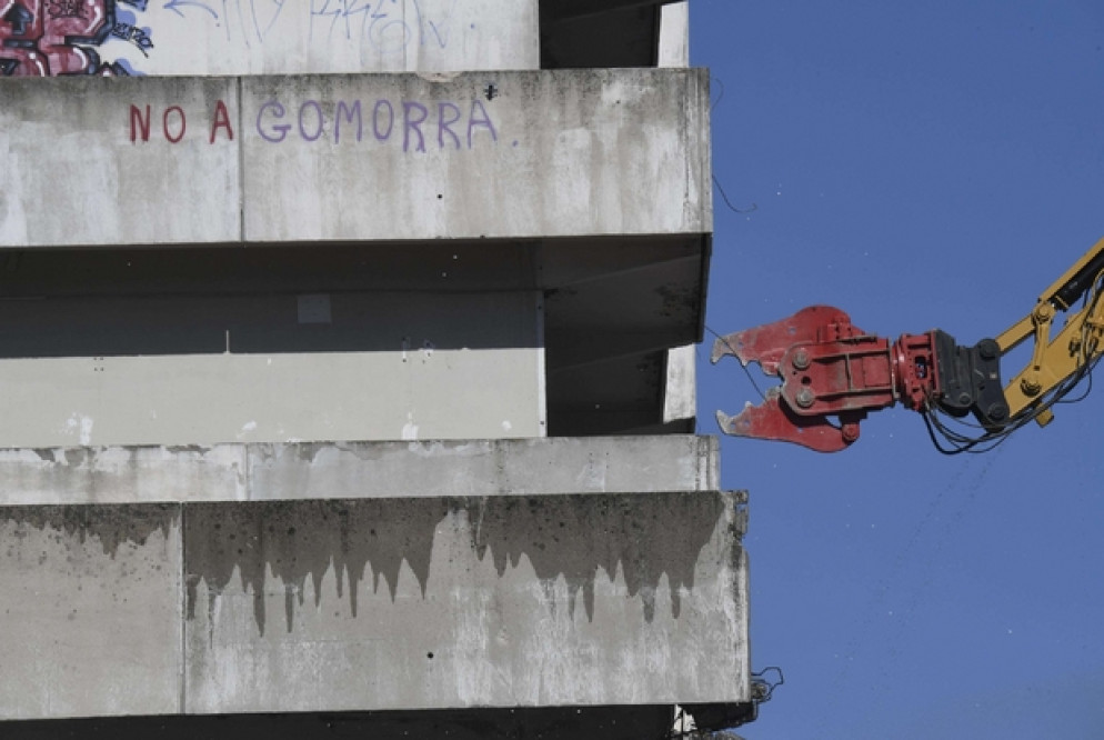 Le ruspe in azione per l'abbattimento della Vela Verde di Scampia. Sul muro si legge: «No a Gomorra» - Ansa