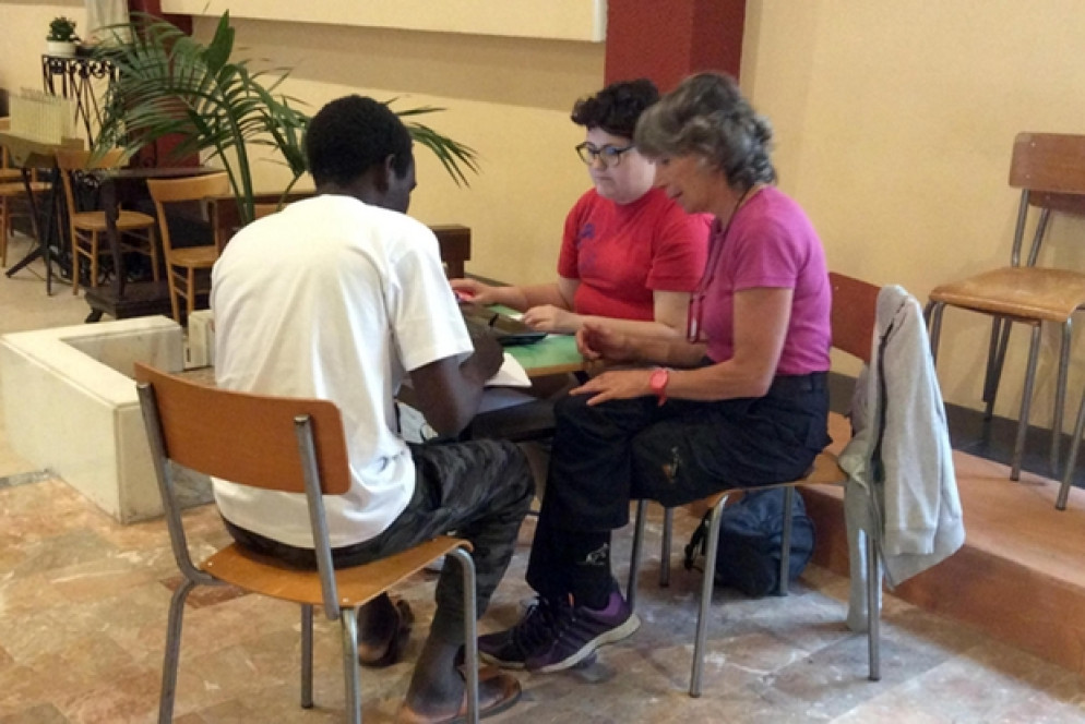 Alcuni volontari della Caritas registrano un profugo nella parrocchia di Sant'Antonio