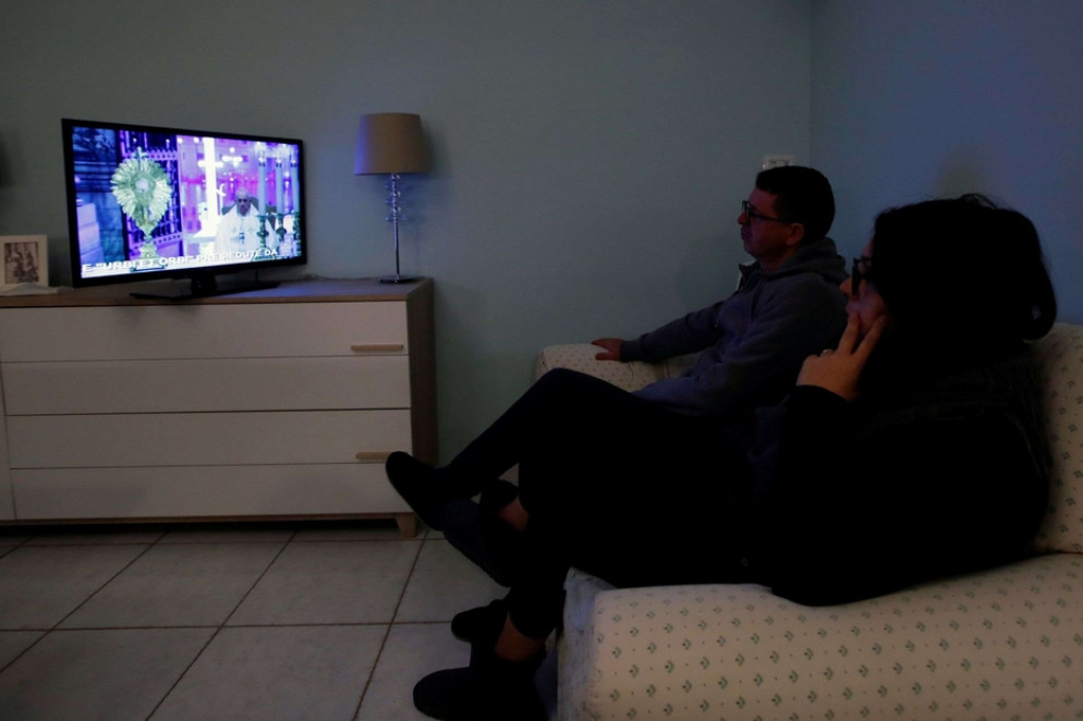 Una famiglia mentre segue in diretta tv la preghiera e la benedizione Urbi et Orbi di papa Francesco - Reuters