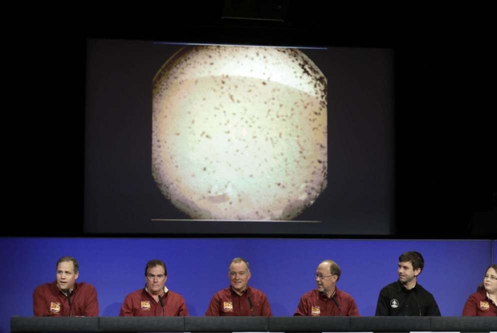 Gli scienziati della Nasa commentano la missione InSight. Alle spalle, le immagini inviate dalla sonda (Ansa)