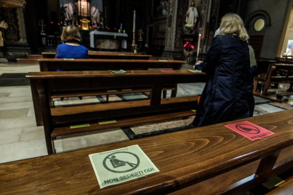 I cartelli sulle panche di una chiesa per mantenere le distanze di sicurezza - Ansa