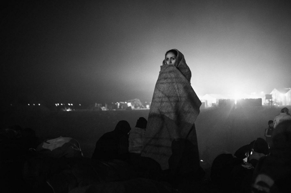 Idomeni, Grecia, 2015. Una donna siriana osserva la rivolta nel campo di Idomeni. ©Alessio Cupelli