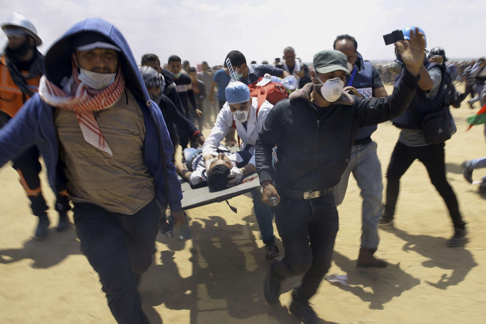 Medici e dimostranti trasportano un giovane ferito a est di Khan Younis, nella Striscia di Gaza (Ansa)