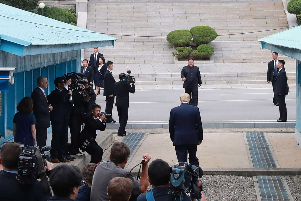 Trump e Kim camminano uno incontro all'altro, a cavallo della linea di confine (Ansa)