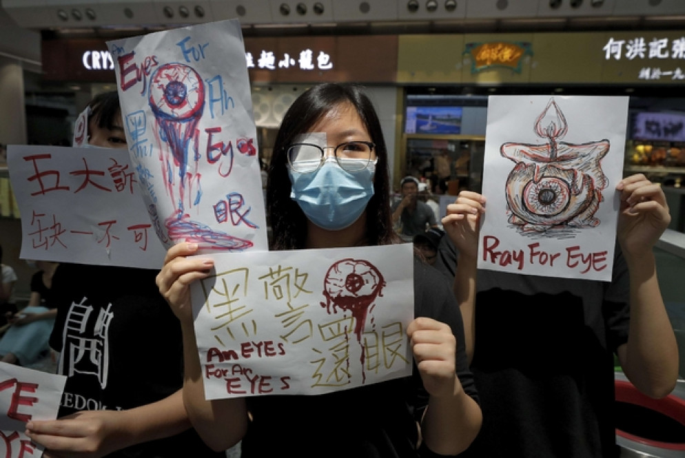 L'aeroporto di Hong Kong occupato dai manifestanti. Un occhio coperto in segno di solidarietà con un manifestante ferito (Ansa)