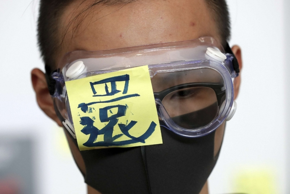 Le proteste a Hong Kong: un uomo copre un occhio in solidarietà con un manifestante colpito dalla polizia (Ansa)
