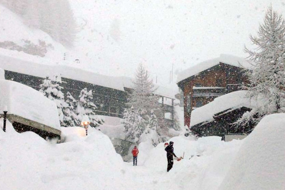 Alcuni turisti si fanno largo tra la neve spalando. La mole di quella caduta sulle case e sulle strade è impressionante