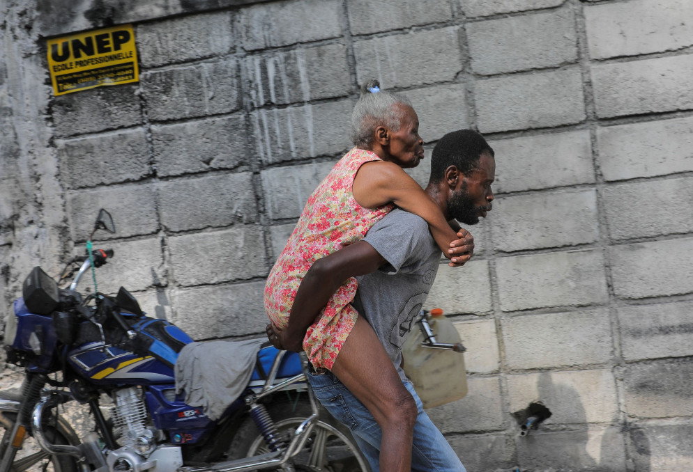 Un giovane cerca di portare via dalla zone degli scontri l'anziana madre - Reuters