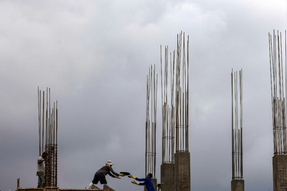 Operai edili al lavoro sotto la pioggia in un cantiere di Kathmandu - ANSA