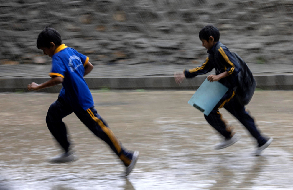 Bambini giocano sotto la pioggia a Kathmandu - ANSA