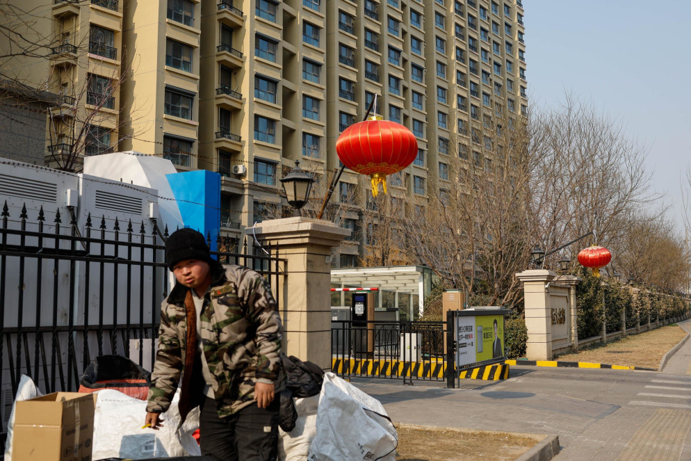 Un addetti alle consegne davanti a un complesso di Evergrande a Pechino - Ansa