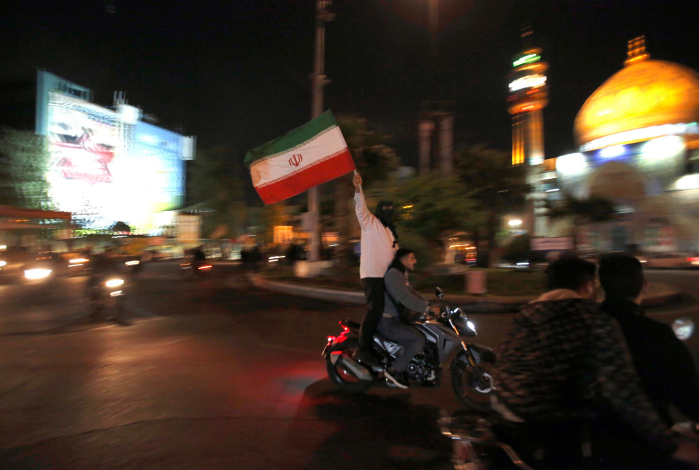 Ragazzi sventolano la bandiera iraniana durante la manifestazione anti-israeliana in piazza Palestina a Teheran scattata subito dopo l'attacco. Alba del 14 aprile 2024. - Reuters