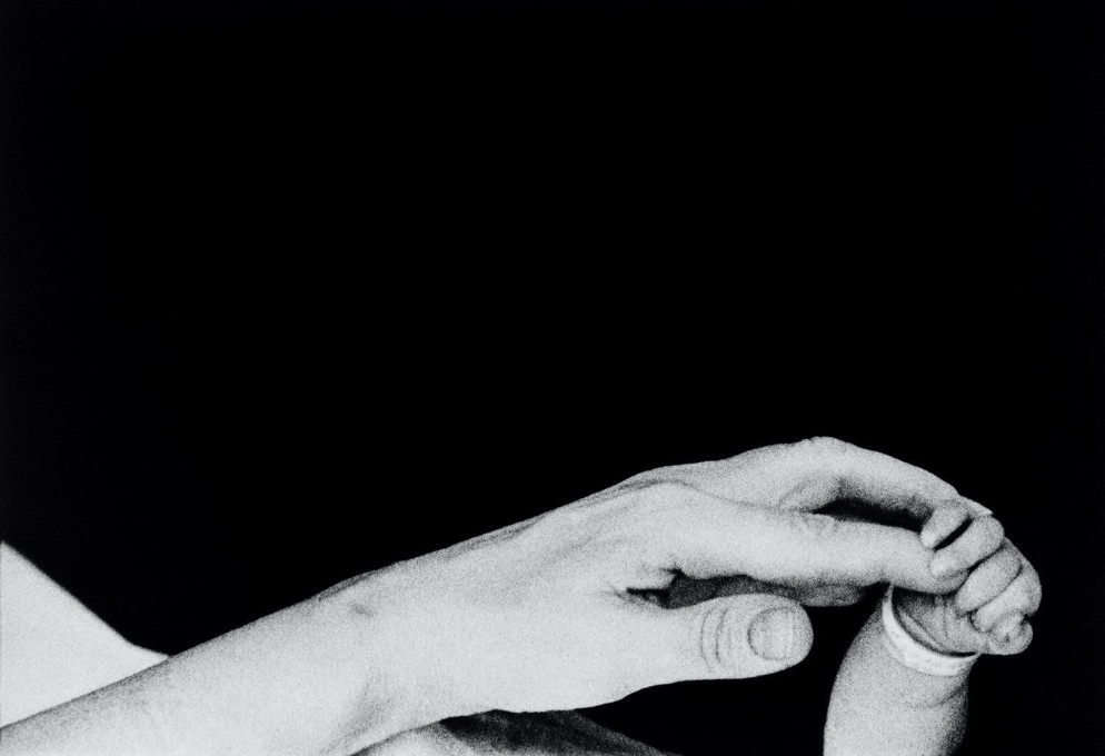 In mostra a Forlì, Musei di San Domenico, "Eve Arnold. L’opera, 1950-1980": i primi cinque minuti di vita di un neonato. Una madre tiene la mano del suo piccolo. New York, Long Island, 1959 - © Eve Arnold / Magnum Photos