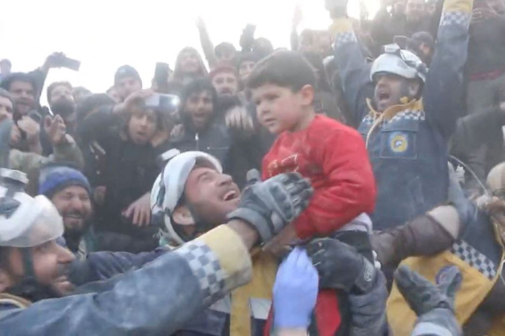 Esultanza per il salvataggio di un bimbo da sotto le macerie, a Bisnia in Siria. Con lui tratti in salvo anche il padre e la sorella - Reuters / Caschi Bianchi (fermo immagine da video)