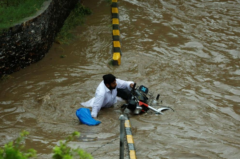 Un uomo cade dalla motocicletta mentre attraversa una strada allagata dai monsoni - Reuters