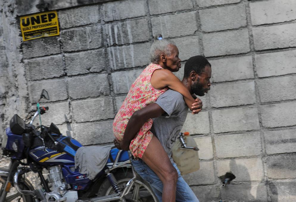 Un giovane cerca di portare via dalla zone degli scontri l'anziana madre - Reuters