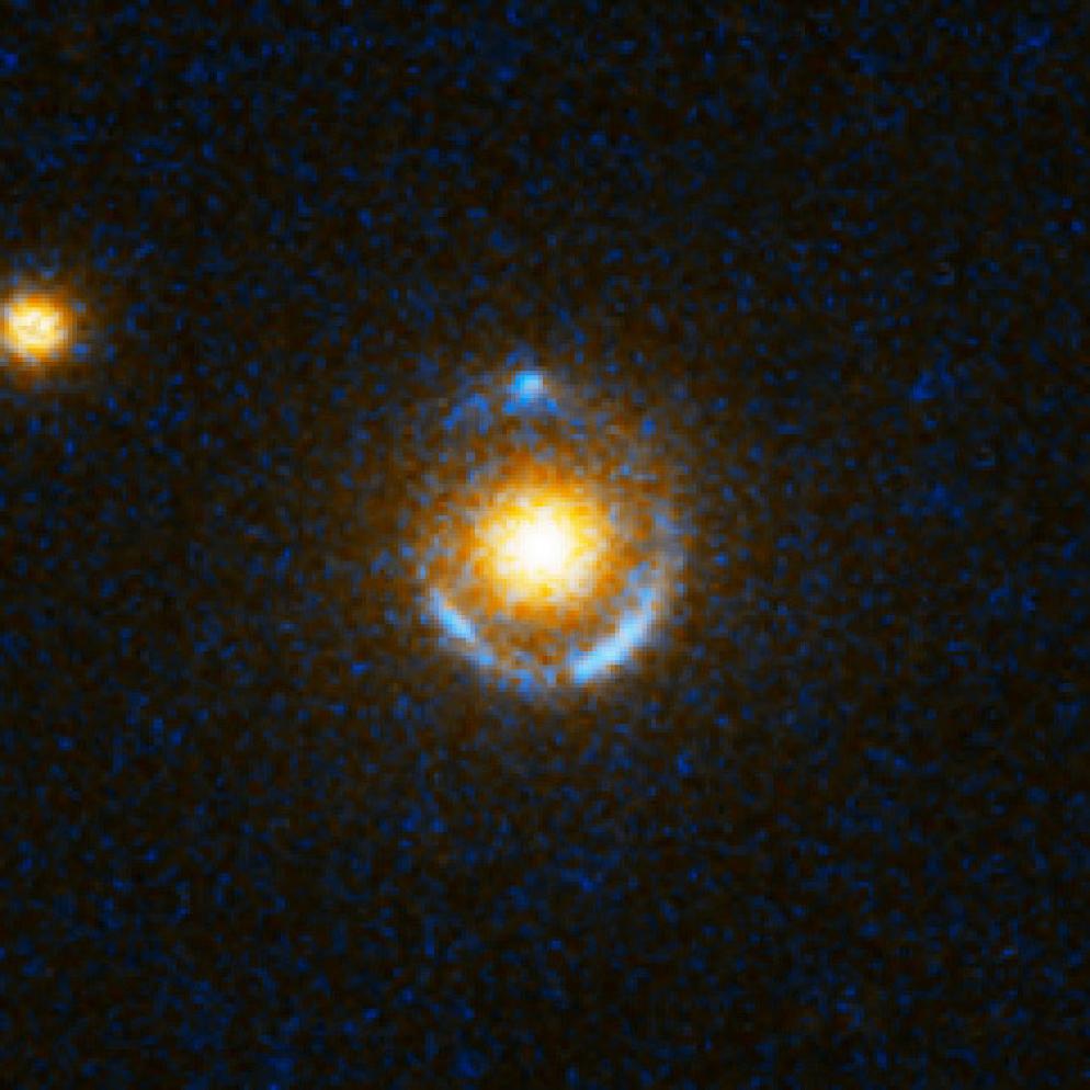 Lente gravitazionale. Le linee azzurre sono il risultato di un oggetto posto dietro il cuore della galassia (gialla) che ha subito l’effetto di lente gravitazionale