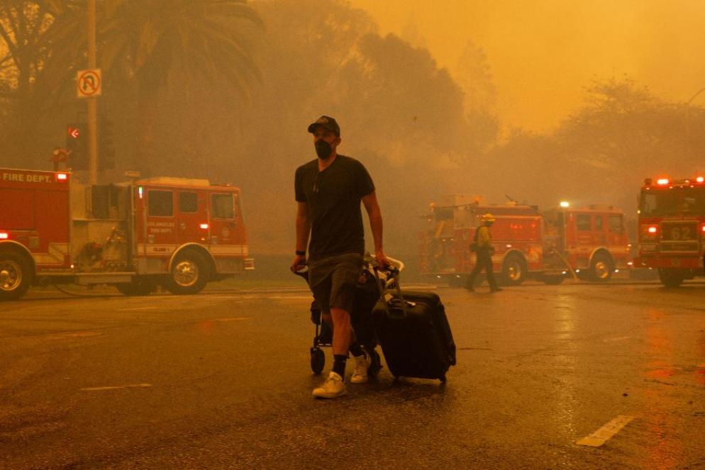 Un residente di Pacific Palisades lascia il quartiere, avvolto dai fumi dell'incendio - Fotogramma