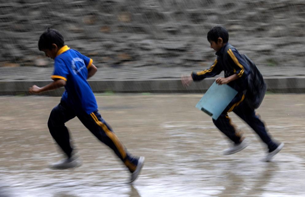 Bambini giocano sotto la pioggia a Kathmandu - ANSA