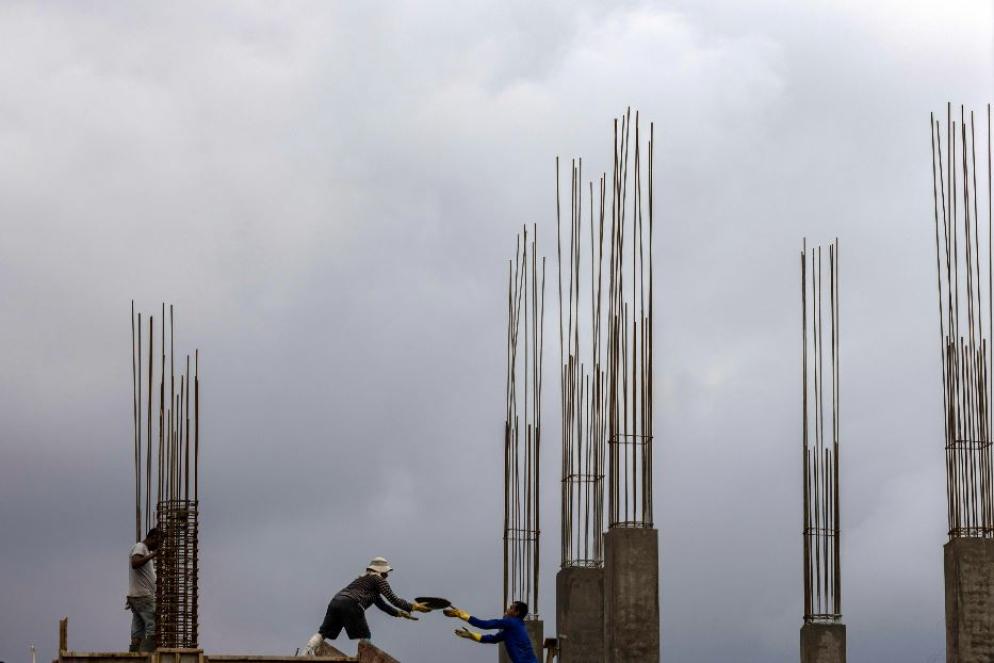 Operai edili al lavoro sotto la pioggia in un cantiere di Kathmandu - ANSA