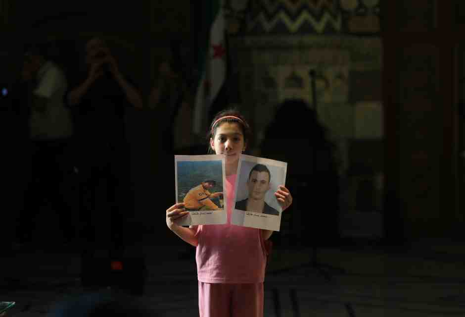 &nbsp;Una bambina mostra le foto di un parente scomparso all'evento del Museo nazionale di Damasco (foto Getty)
