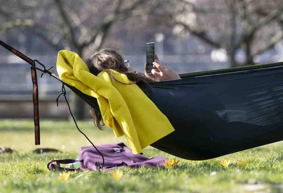 Una donna scorre lo smartphone sdraiata su un'amaca (Foto di Sebastian Kahnert/picture alliance via Getty Images)&nbsp;<br />