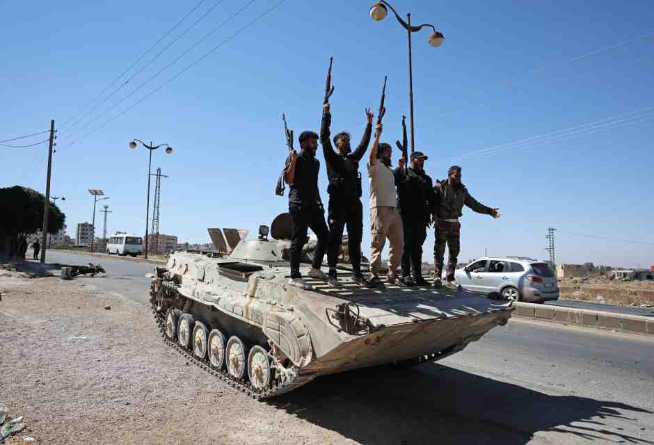 Le forze governative esultano in piedi su un carro armato a Suwayda (foto Getty)