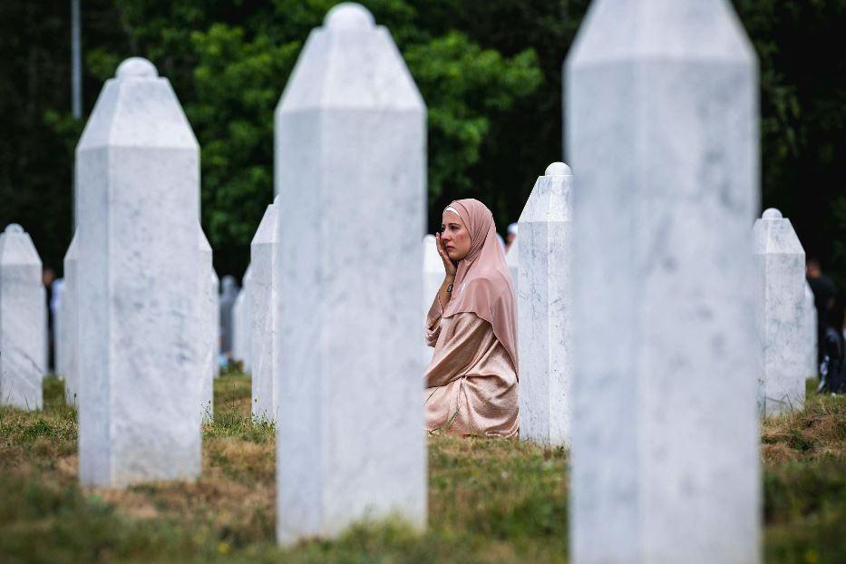 Una donna siede in mezzo alle lapidi del cimitero-memoriale di Srebrenica - ANSA
