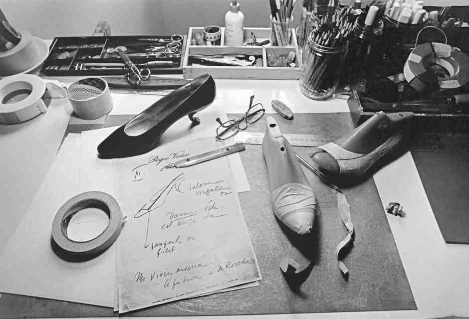 Il tavolo di lavoro di Roger Vivier e un modello di calzatura con il tacco &ldquo;virgule&rdquo; nel suo atelier a Toulouse,&nbsp;nel 1984 (courtesy maison Vivier).
