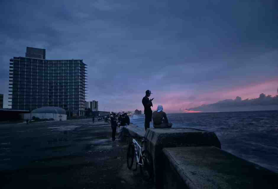L'Avana: persone in piedi sulla riva davanti agli edifici spenti (Foto di Nick Kaiser/picture alliance)&nbsp;<br />